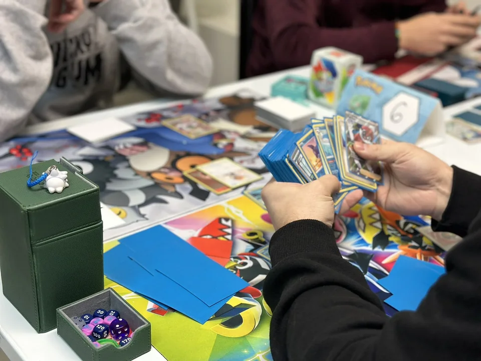 Partita di Pokémon TCG al tavolo, con mazzi e dadi
